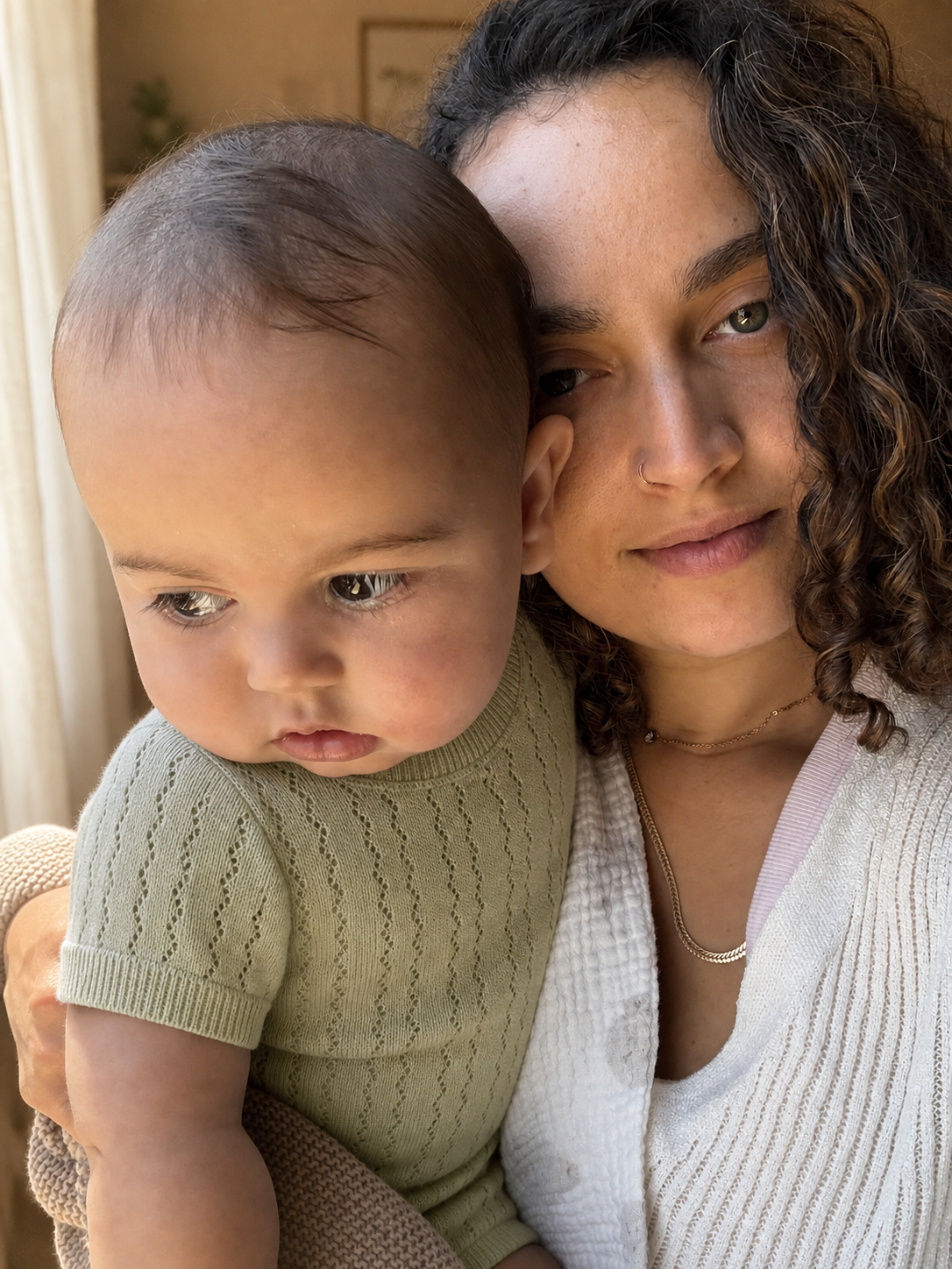 Orel, founder of GentleNest, holding her baby in a soft sage knit romper.
