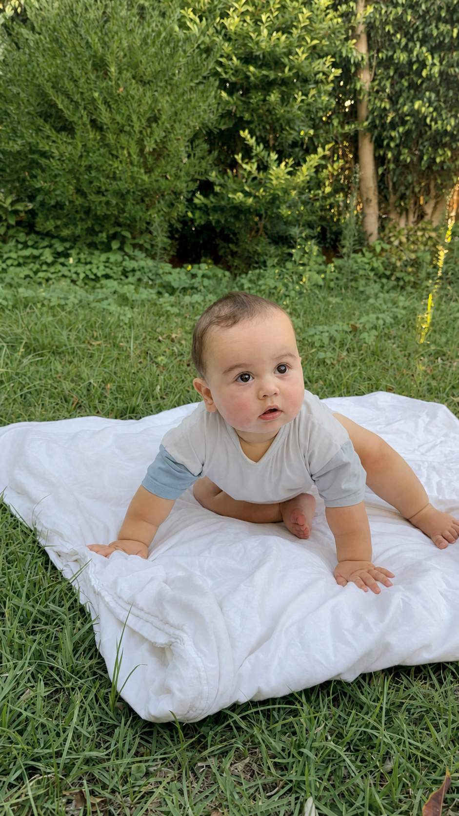 Baby wearing a soft GentleNest blue romper while playing outdoors on a blanket.